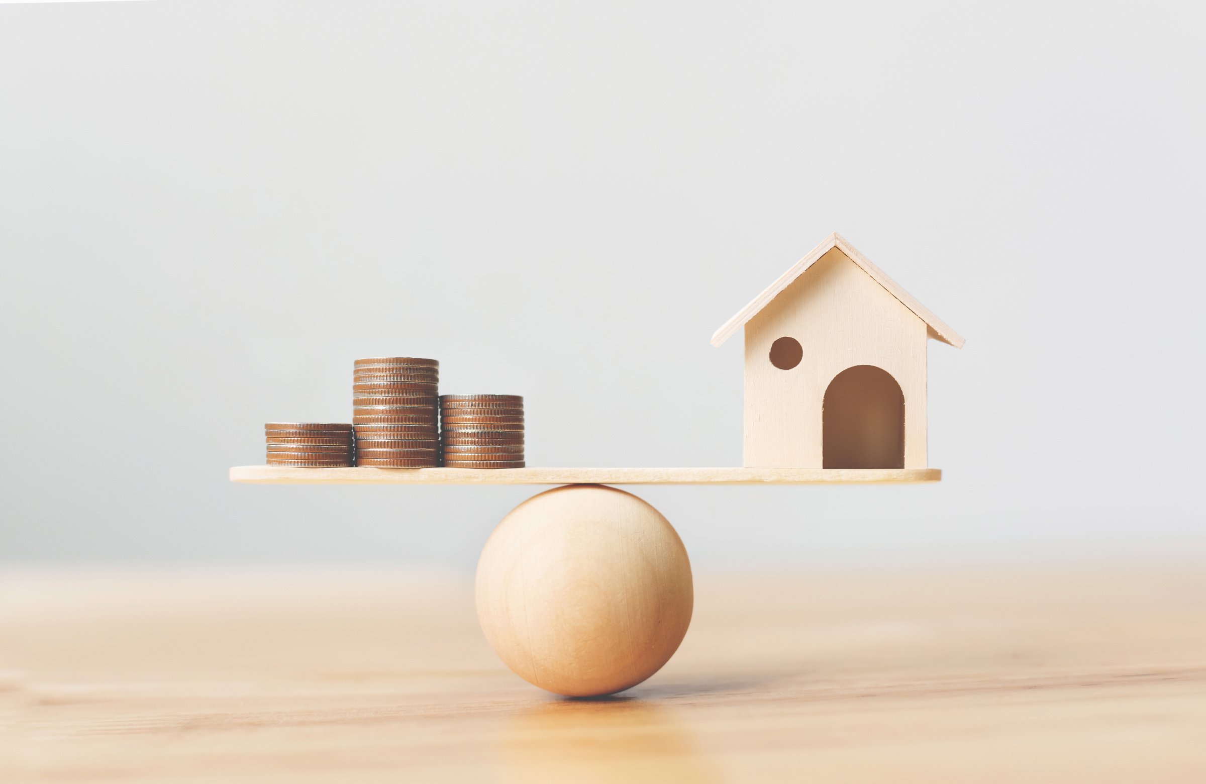 Wooden Home and Money Coins Stack on Wood Scale. Property Invest